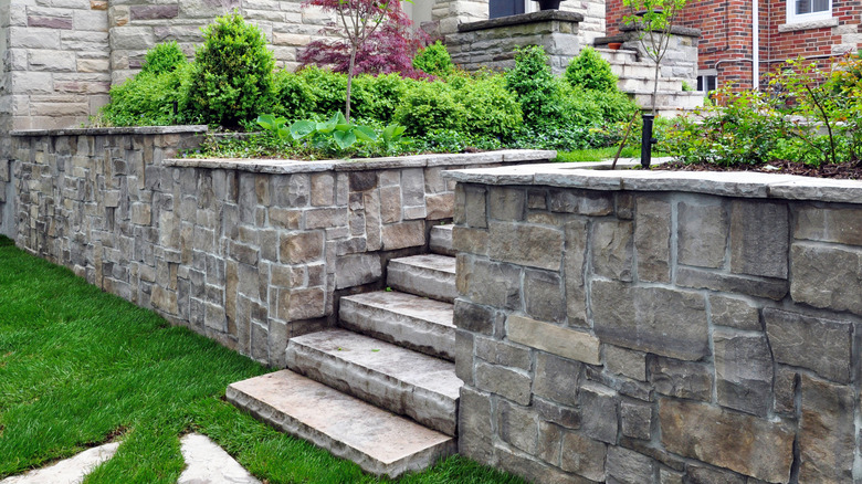 A natural stone retaining wall with several steps leading up in the middle