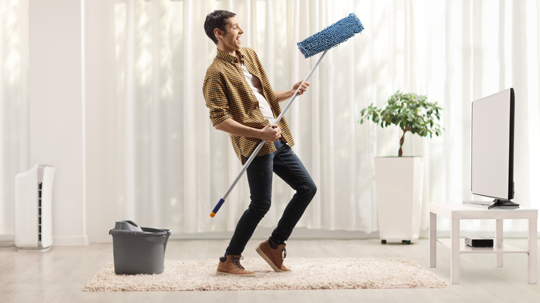 Happy man dancing with mop