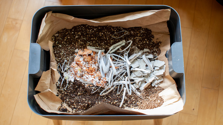 A vermicomposting system is shown with bedding material, soil, and food scraps