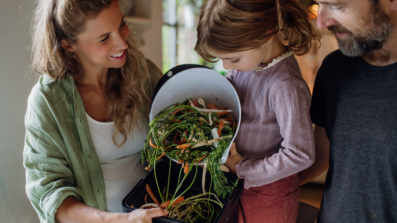 A family adds food scraps to a compost bin