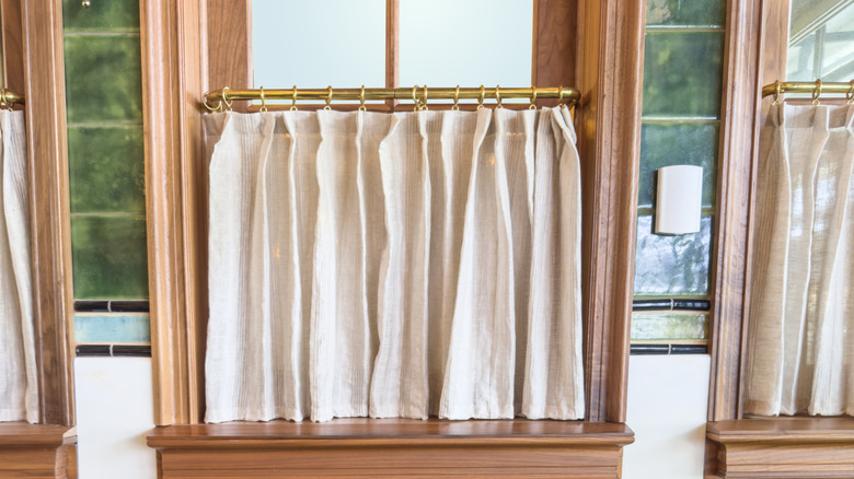 Pleated cafe curtains on brass rods and rings.