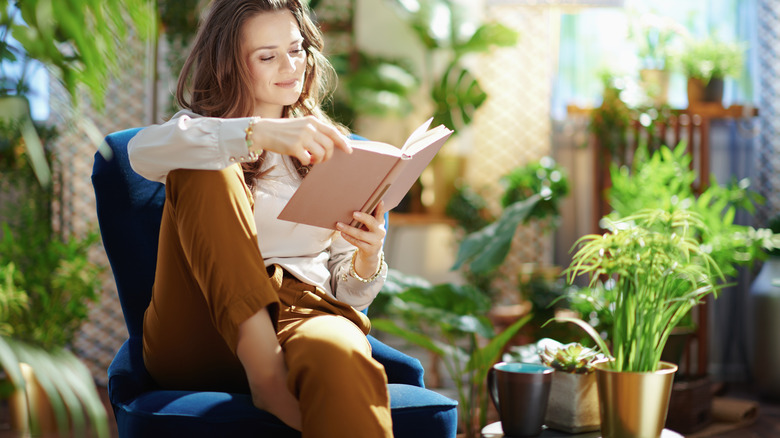 woman reading book with plants