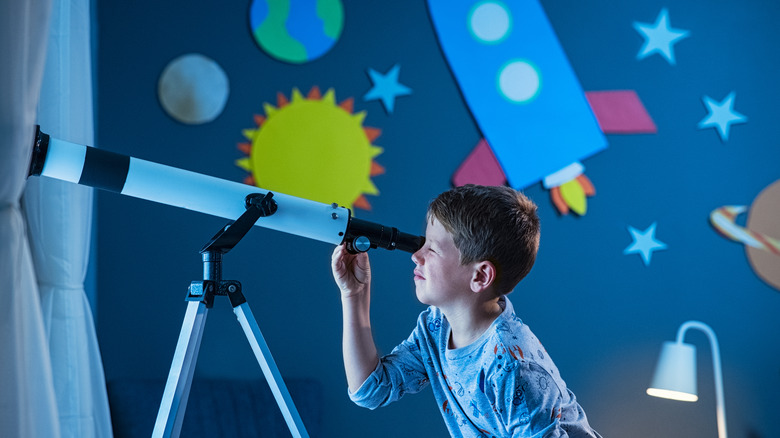 boy using telescope in bedroom