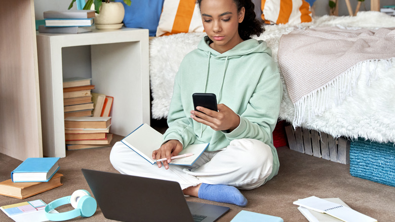 Young girl doing homework on bedroom floor