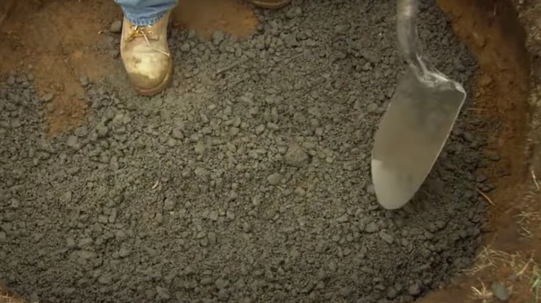 Person shovelling stones in hole