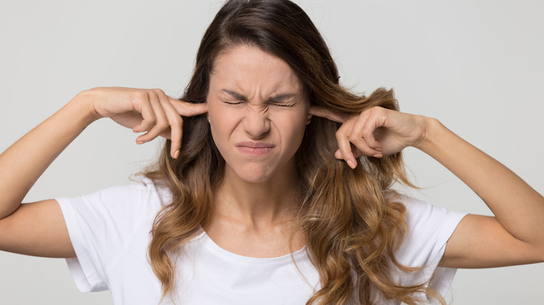 woman frowning and plugging ears