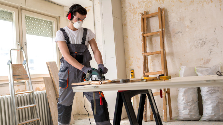 Person cutting door with saw