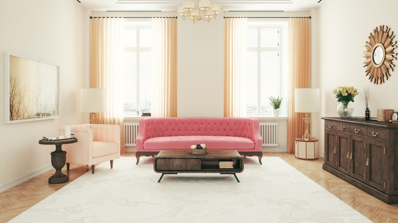 Pink tufted sofa in white room with dark wood coffee table