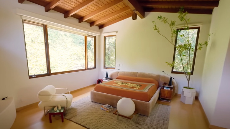 Bedroom with interestingly shaped headboard, plant holder and chair