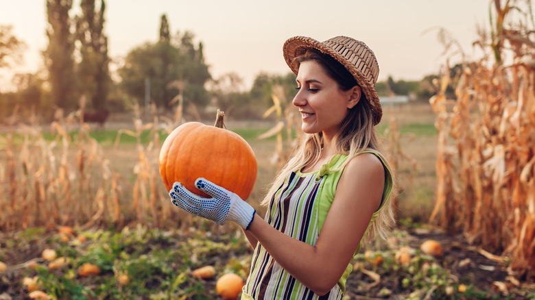 Woman holding pumpkin in field