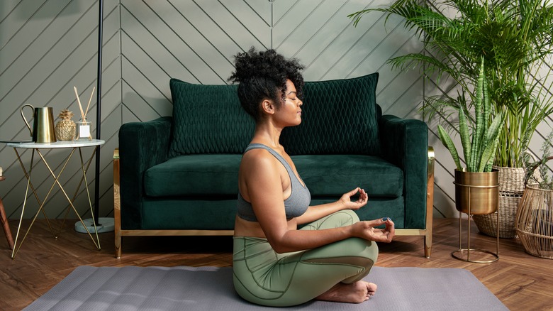 Woman meditating by green couch