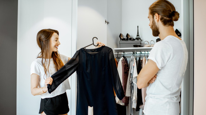 Young couple picking out dress clothes from a closet