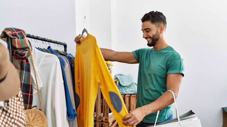 happy man buying trendy clothes on a rail