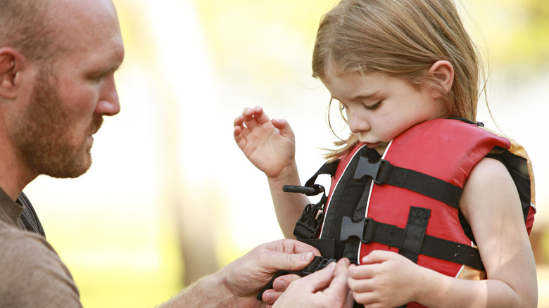 dad helping daughter with lifejacket