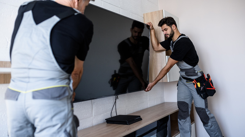 Two people mounting TV