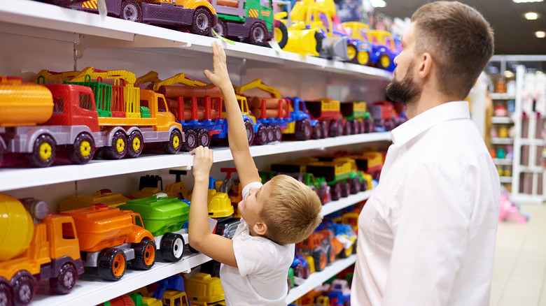 child reaching for toys on shelf
