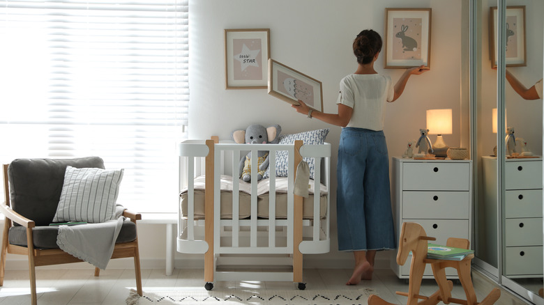 woman hangs photo in nursery 