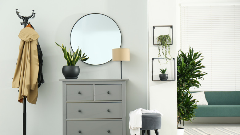 circular mirror above gray dresser