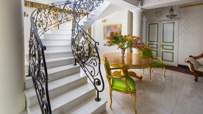 wrought-iron staircase railings rise over a marble floor