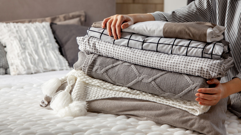 woman holding stack of linens