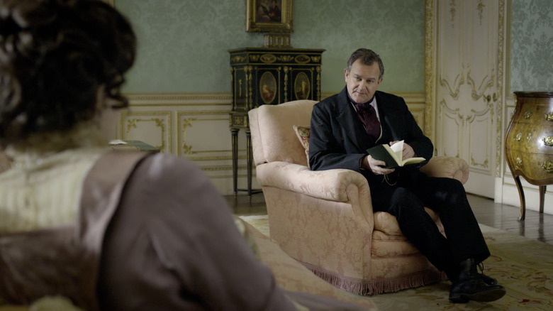 Earl of Grantham sitting in Cora's drawing room reading a book