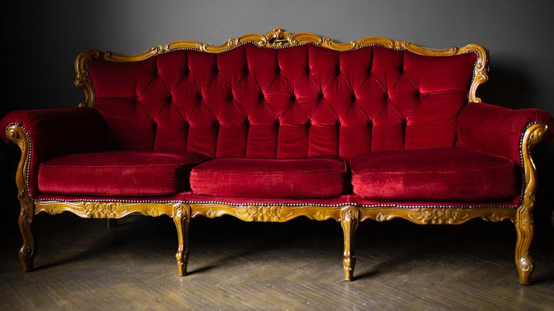 Red velvet couch with gold details.