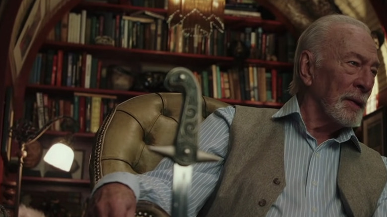 Christopher Plummer sits near old bookcase in "Knives Out"