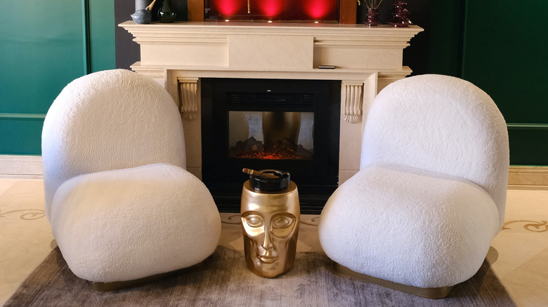 two white chairs by fireplace