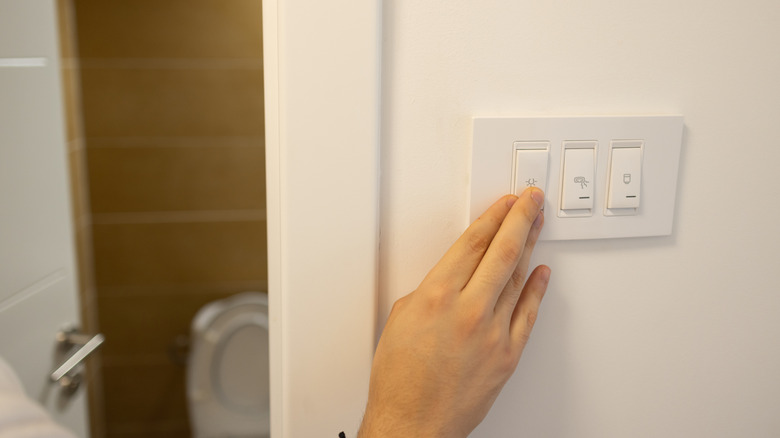 Hand turning off bathroom light switch