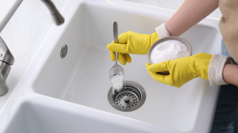 person putting baking soda in drain