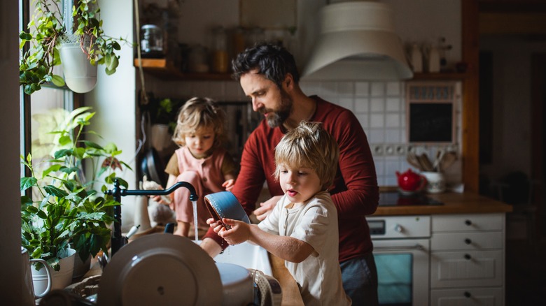 man with children doing dishes