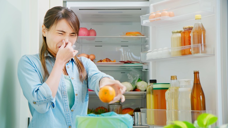 woman cleaning out food in refrigerator