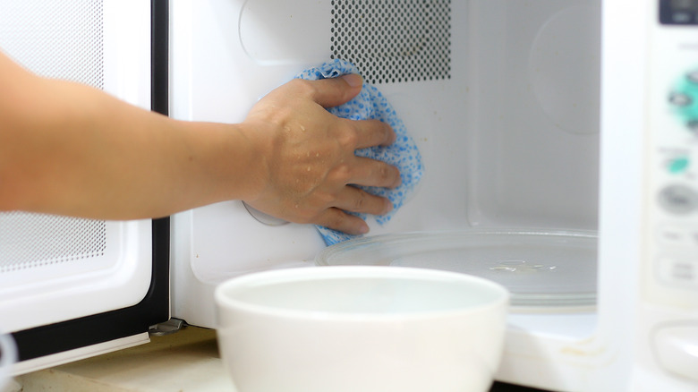 man cleaning inside of microwave
