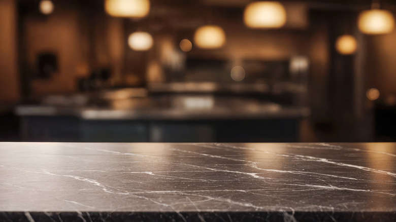 Black marble countertop in the foreground with a blurry room in the background