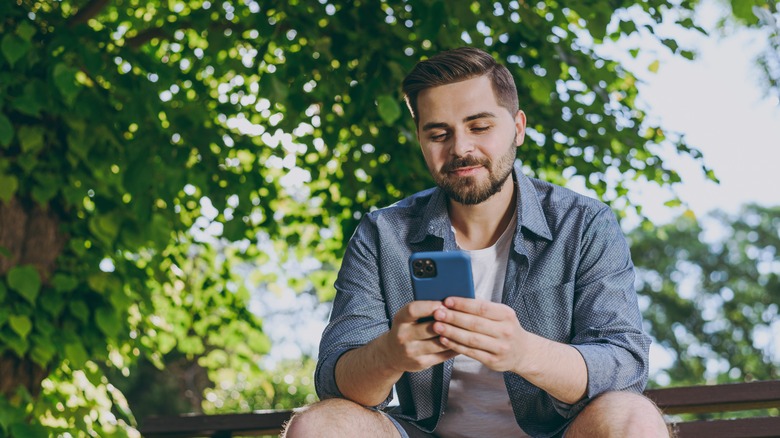 A person sits outside using their phone.