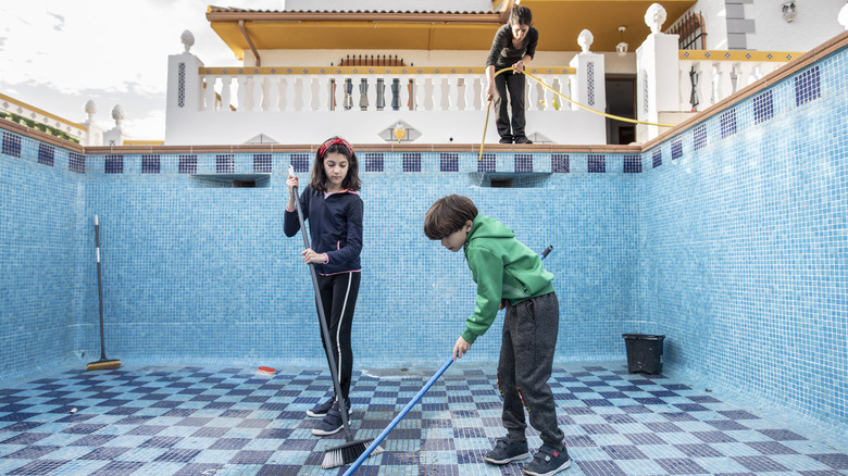 Family cleaning an empty pool