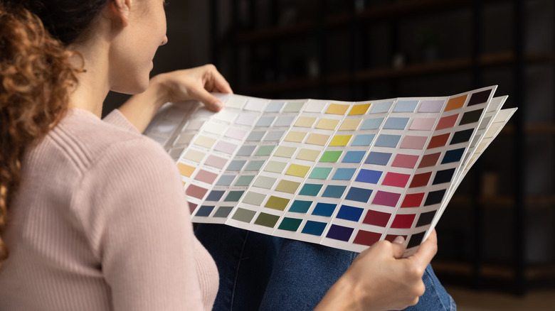 A woman is sitting on the floor looking at paint swatches.