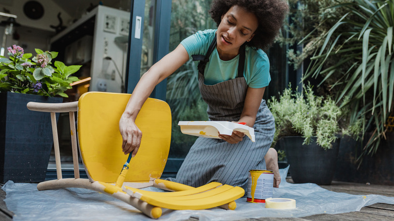 Woman painting chair yellow 