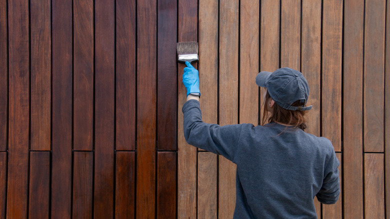 Woman staining a wood fence