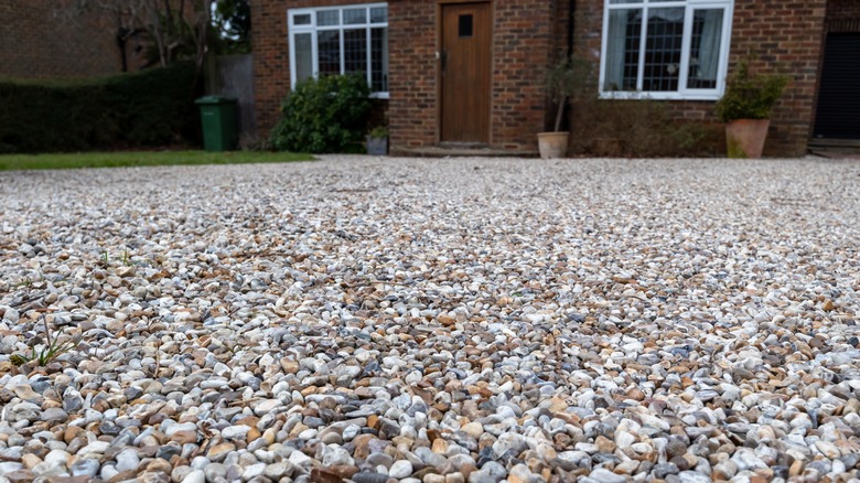 A gravel driveway leads up to a brick house.