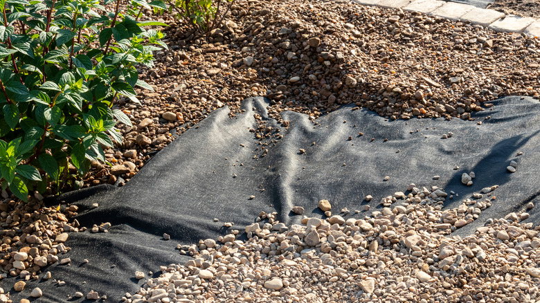 Gravel is being installed over a fabric underlayment.