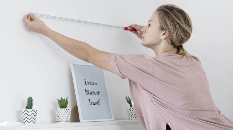 woman measuring wall