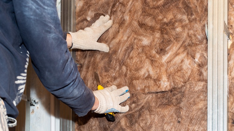 Person placing insulation in wall