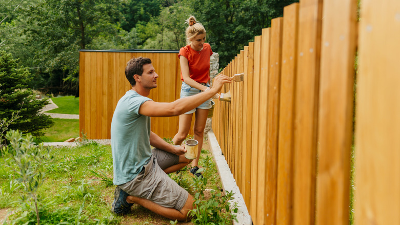 Couple painting fence