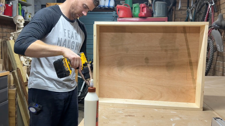 Man using drill to screw in cabinet frame