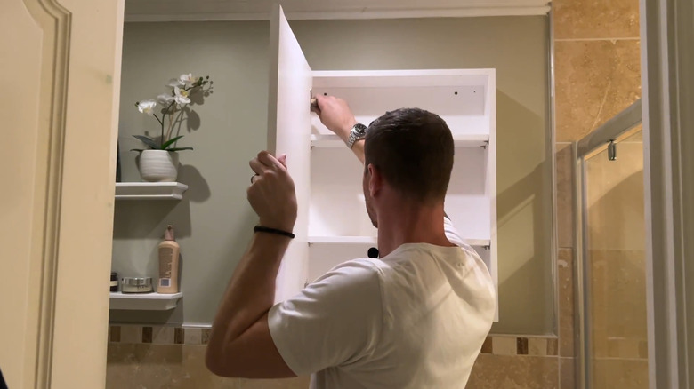 Man installing a bathroom cabinet with storage