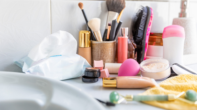 A messy bathroom counter full of cosmetics