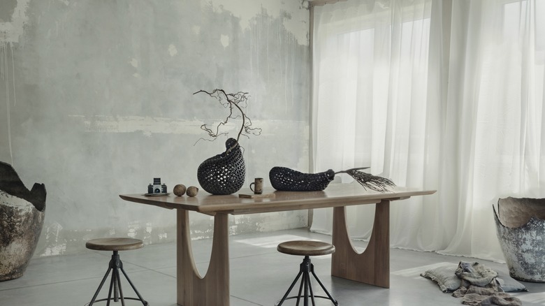 Light gray concrete accent wall in a room with a table and stools