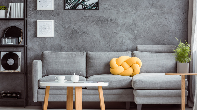 Concrete textured gray wall behind a gray couch in a living room