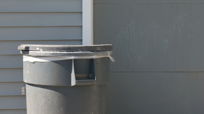 Gray trash can outside the garage of a gray house